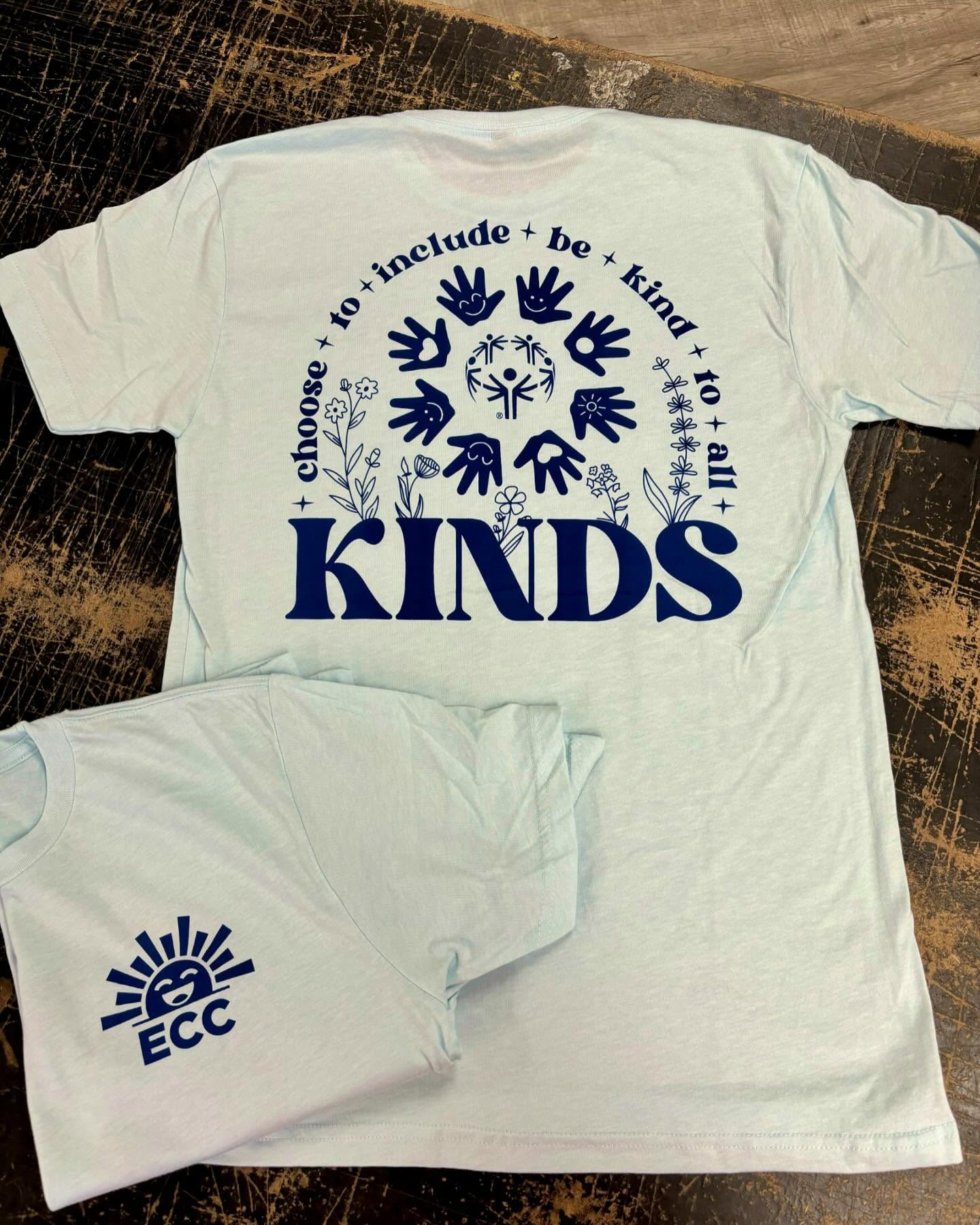 Light blue T-shirt with "Choose to include, be kind to all" text and hand-drawn handprints.