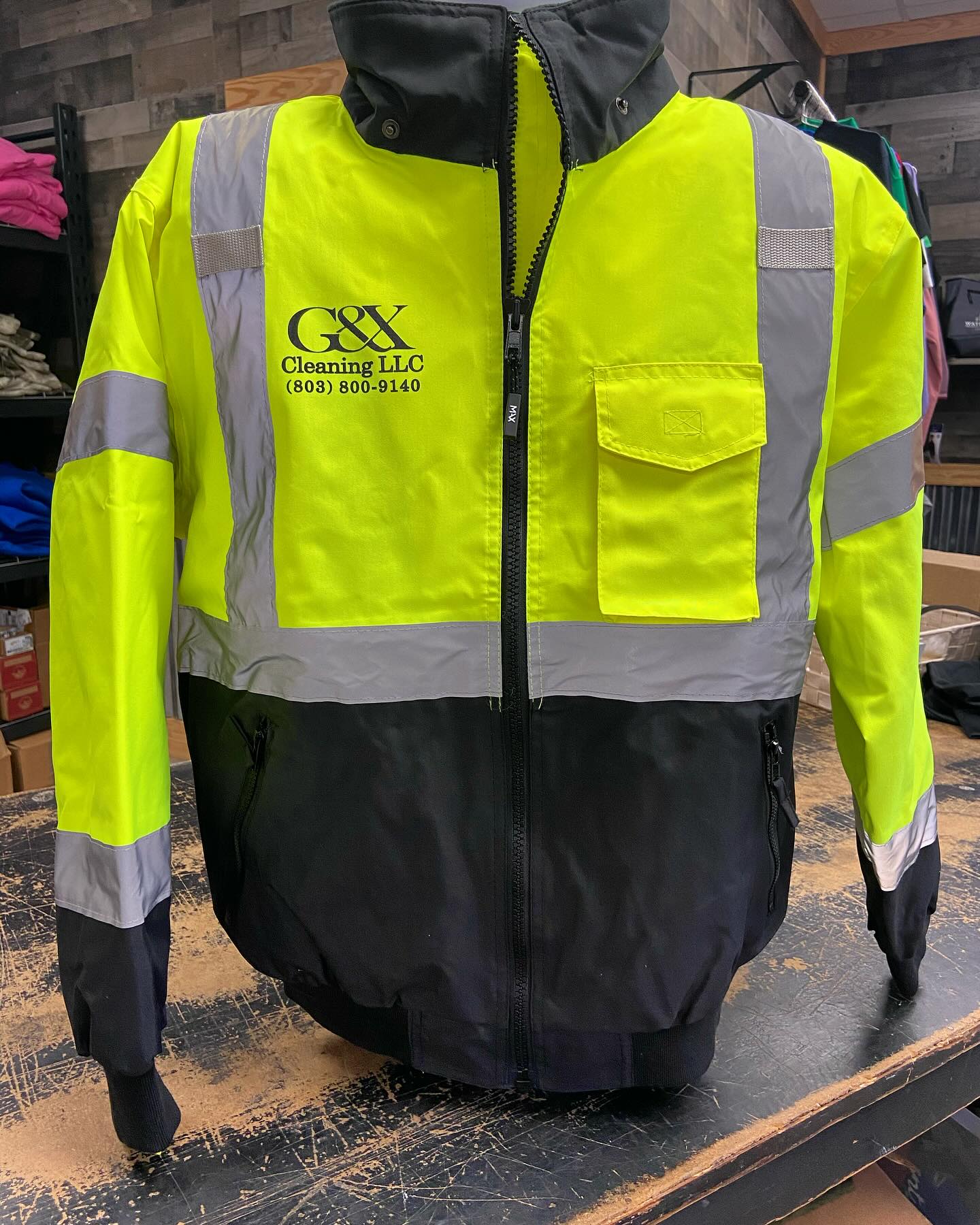 Neon yellow and black high-visibility work jacket with G&X Cleaning LLC branding.