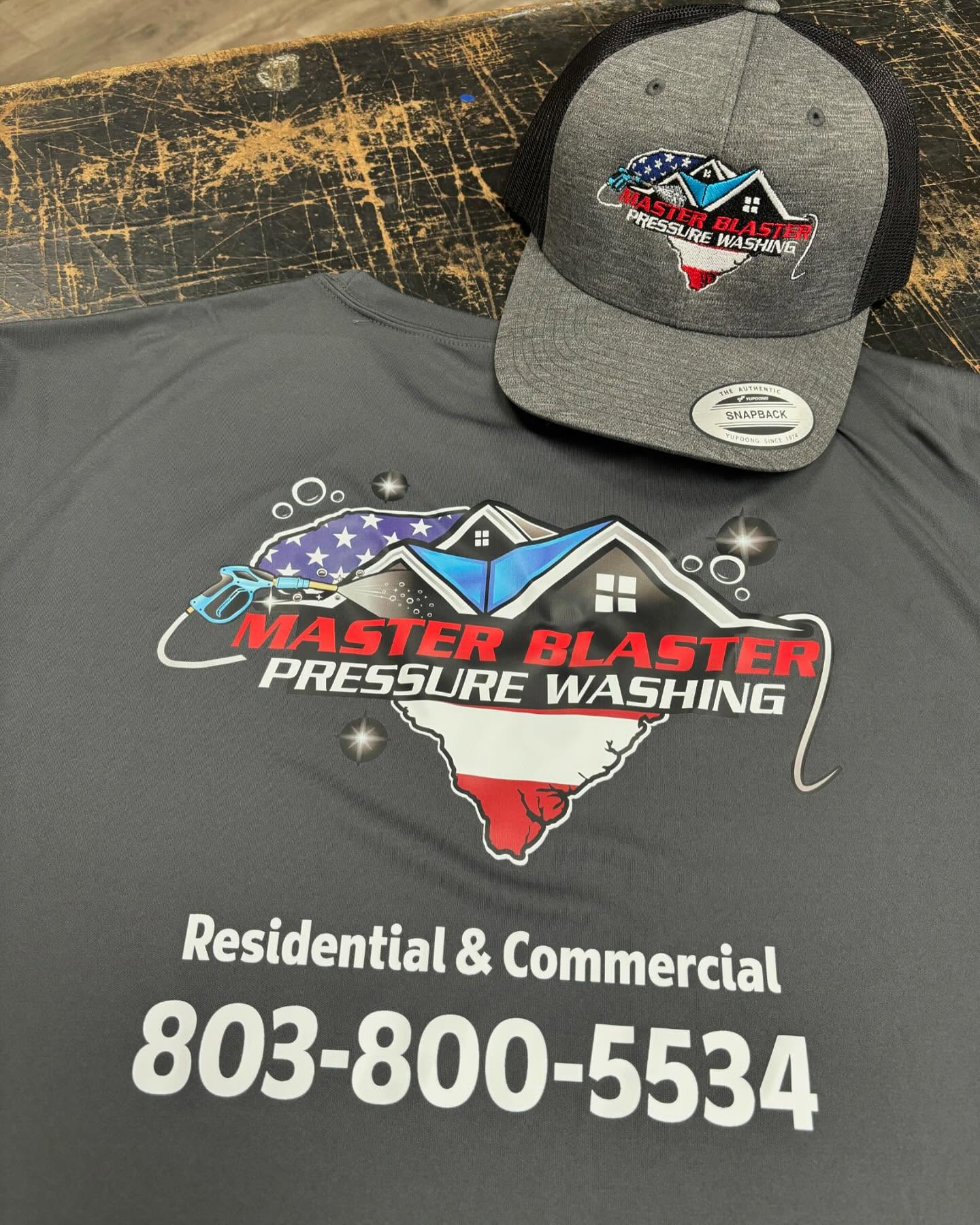Gray moisture-wicking work shirt and snapback trucker hat featuring the Master Blaster Pressure Washing logo.