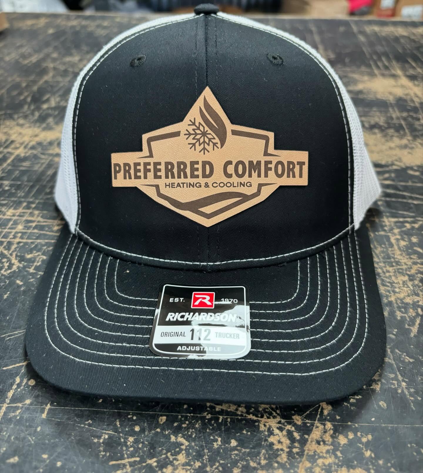 Black and white Richardson 112 trucker hat with a leather patch for Preferred Comfort Heating & Cooling.