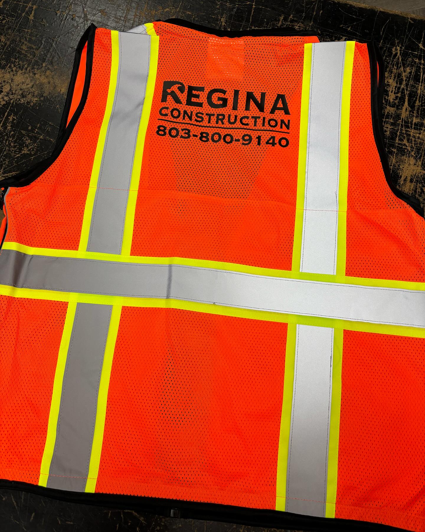 High-visibility orange and reflective safety vest with Regina Construction branding and contact information.