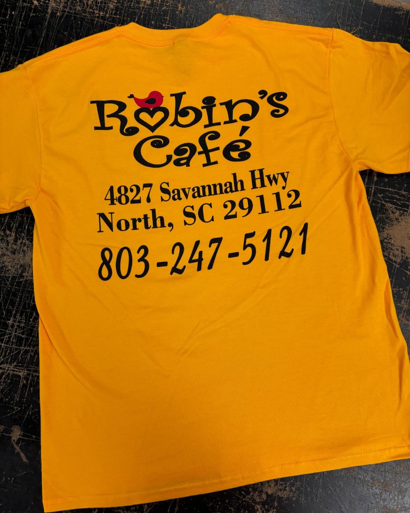 Bright yellow T-shirt featuring Robin’s Café logo and address.