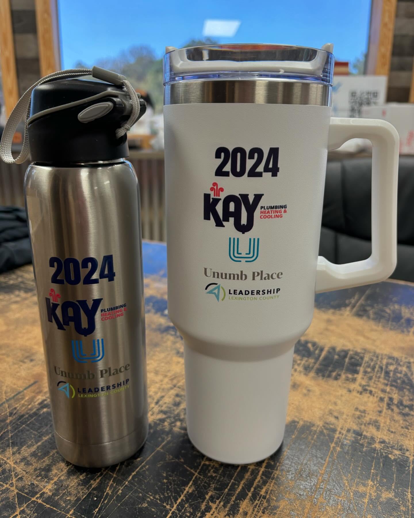 Stainless steel water bottle and white tumbler featuring Unumb Place Leadership Lexington County branding.